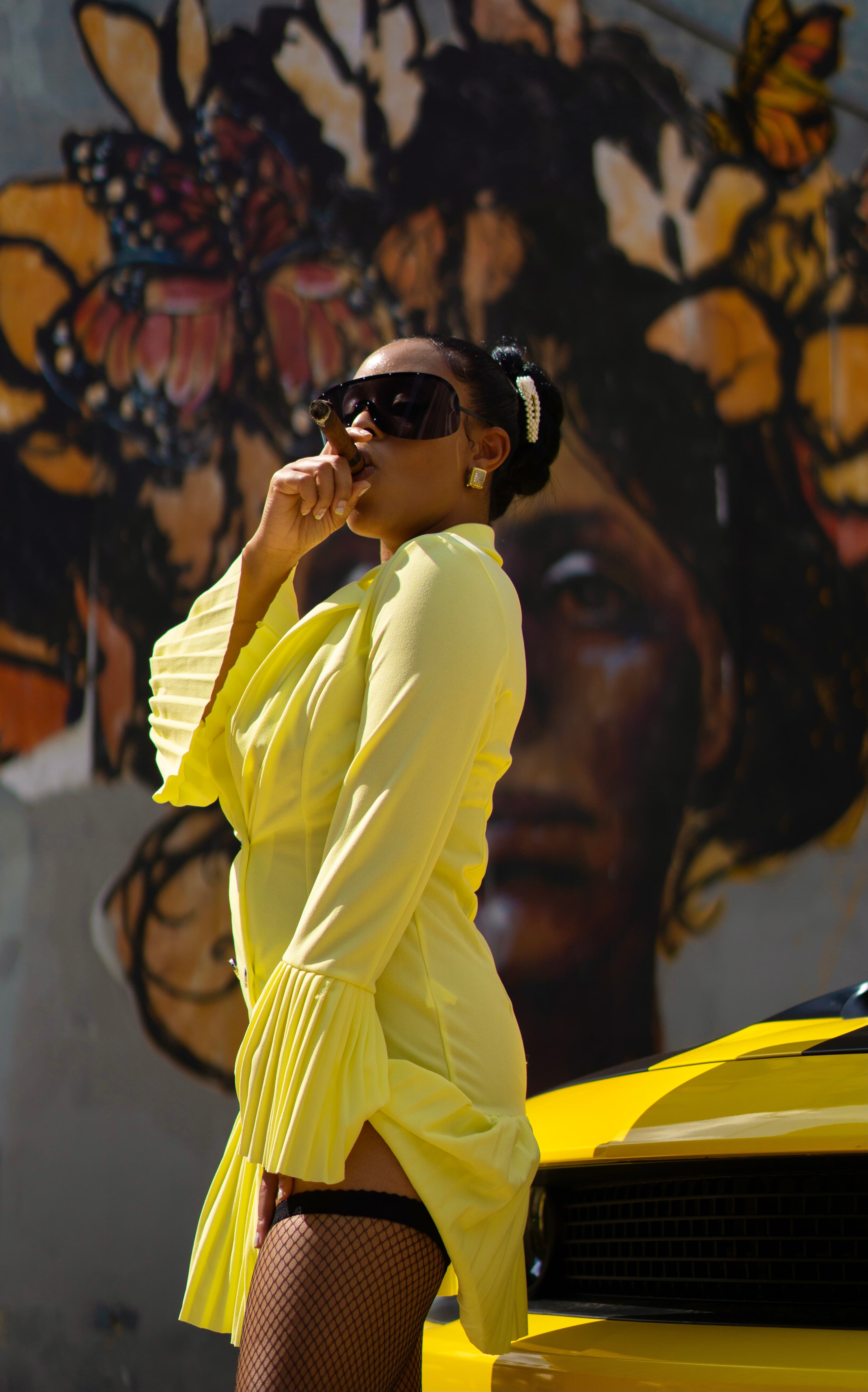 Lifestyle editorial, woman in yellow dress by mural and yellow car
