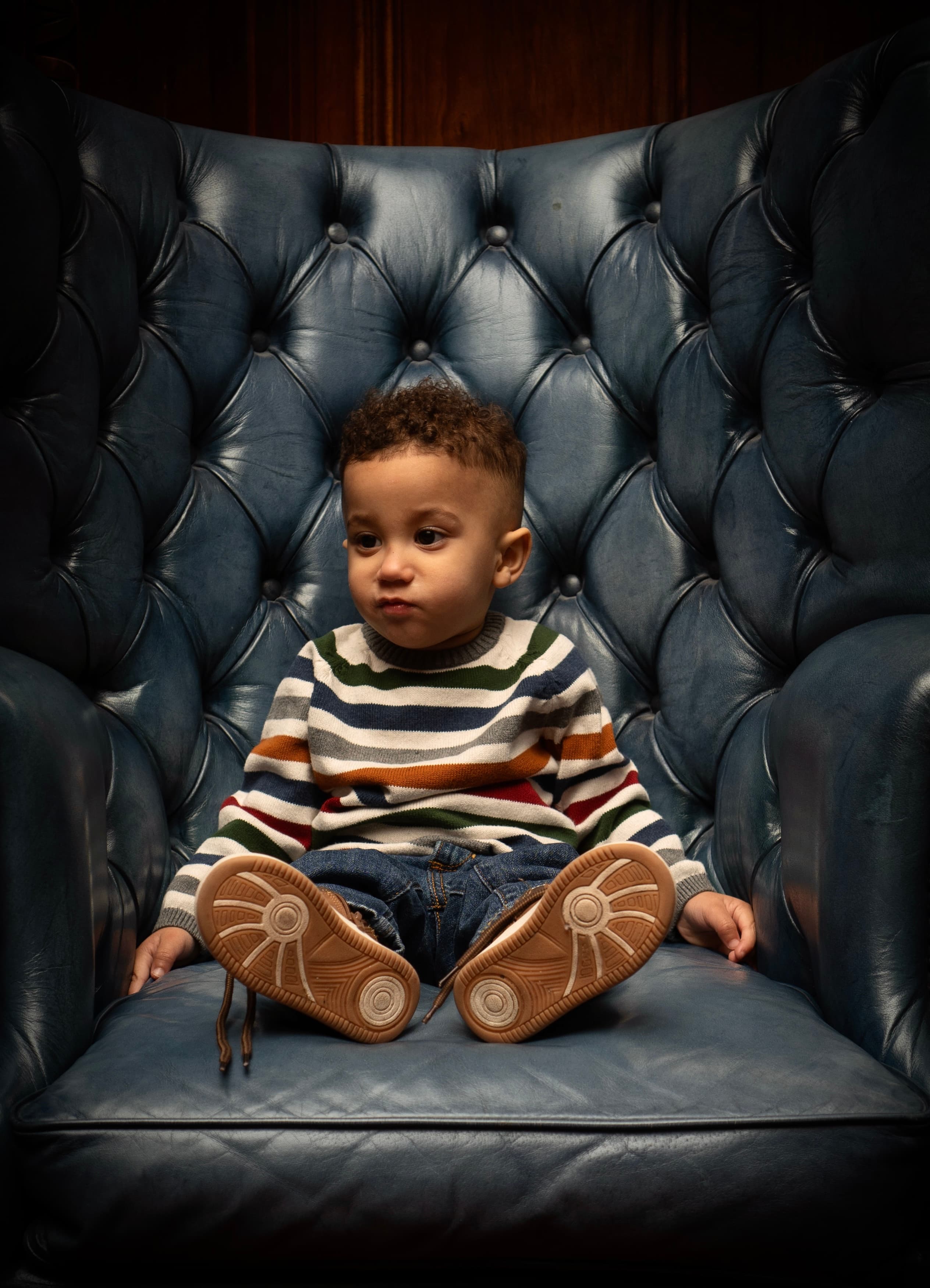 Child portrait, toddler in striped sweater seated in leather chair