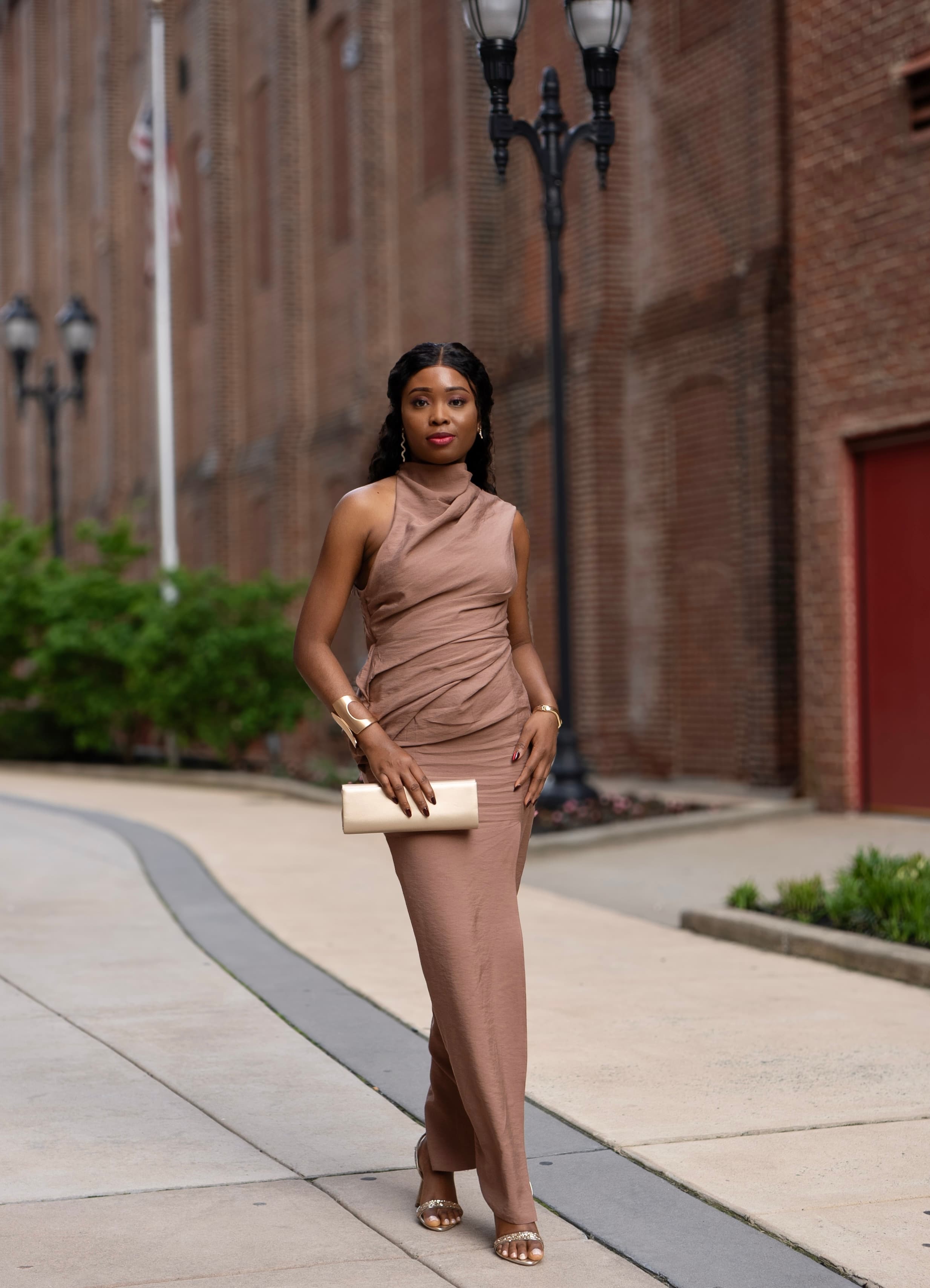 Street editorial, woman in draped brown gown on brick sidewalk