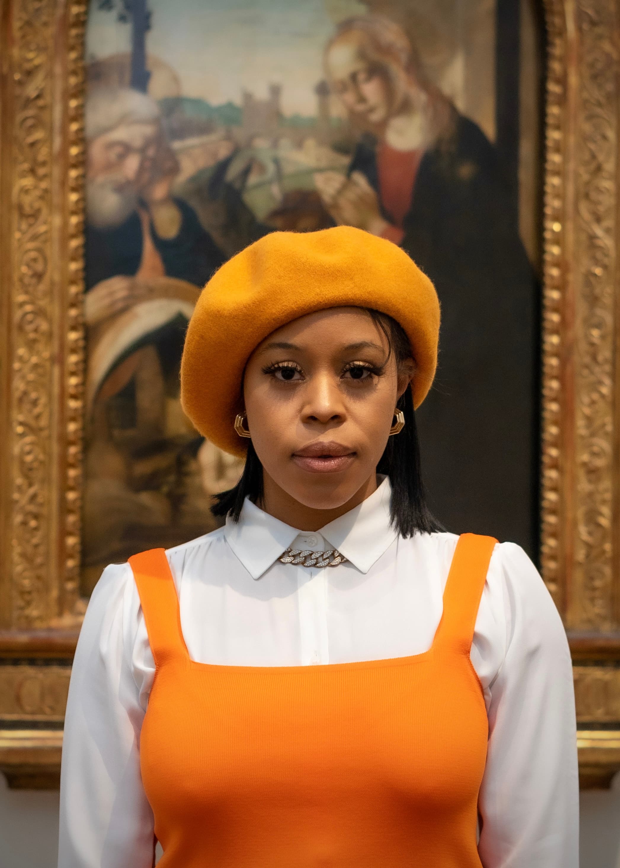 Editorial portrait, woman in orange beret before classical painting
