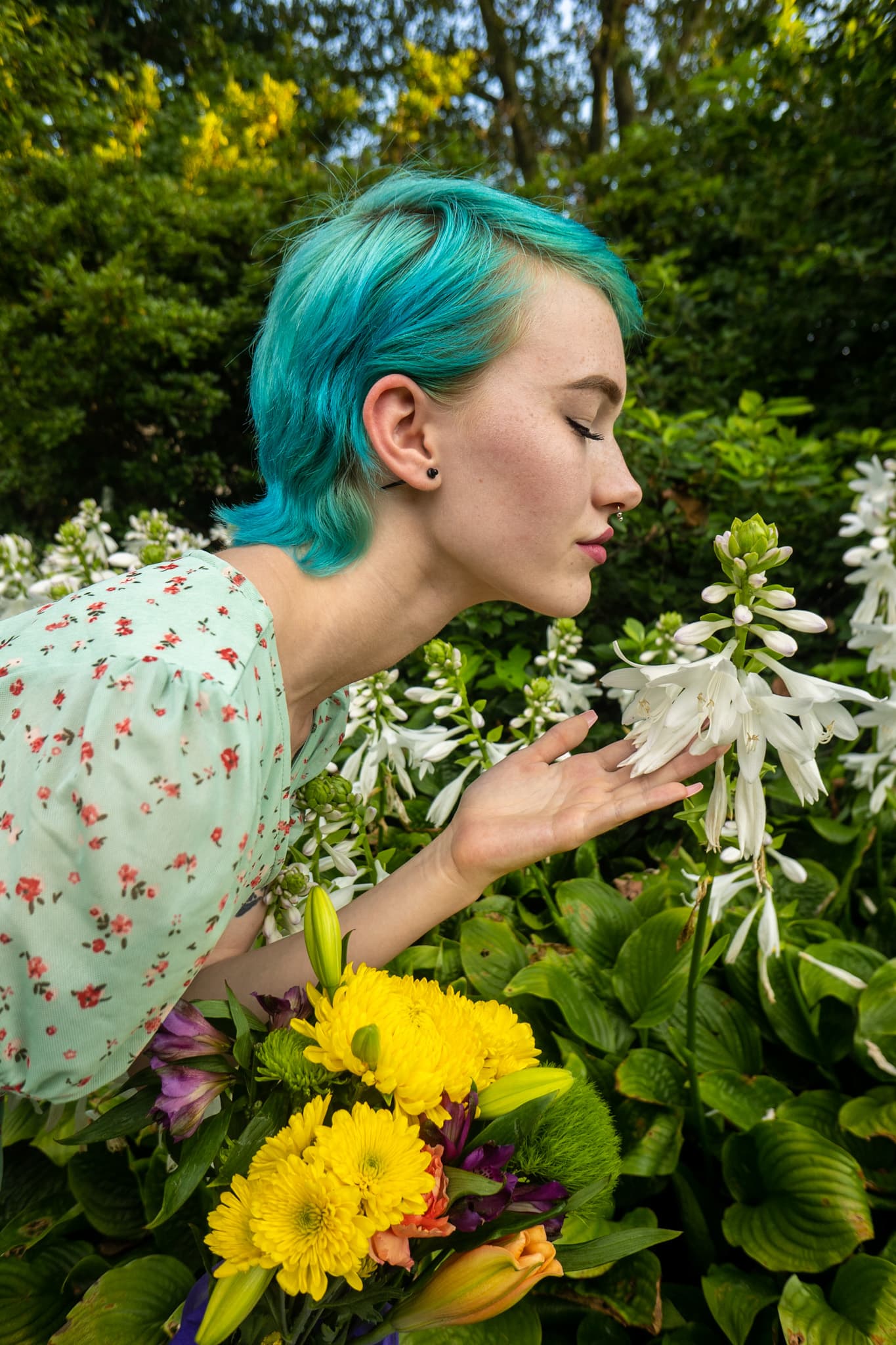 Lifestyle, woman with teal hair in floral dress among garden blooms