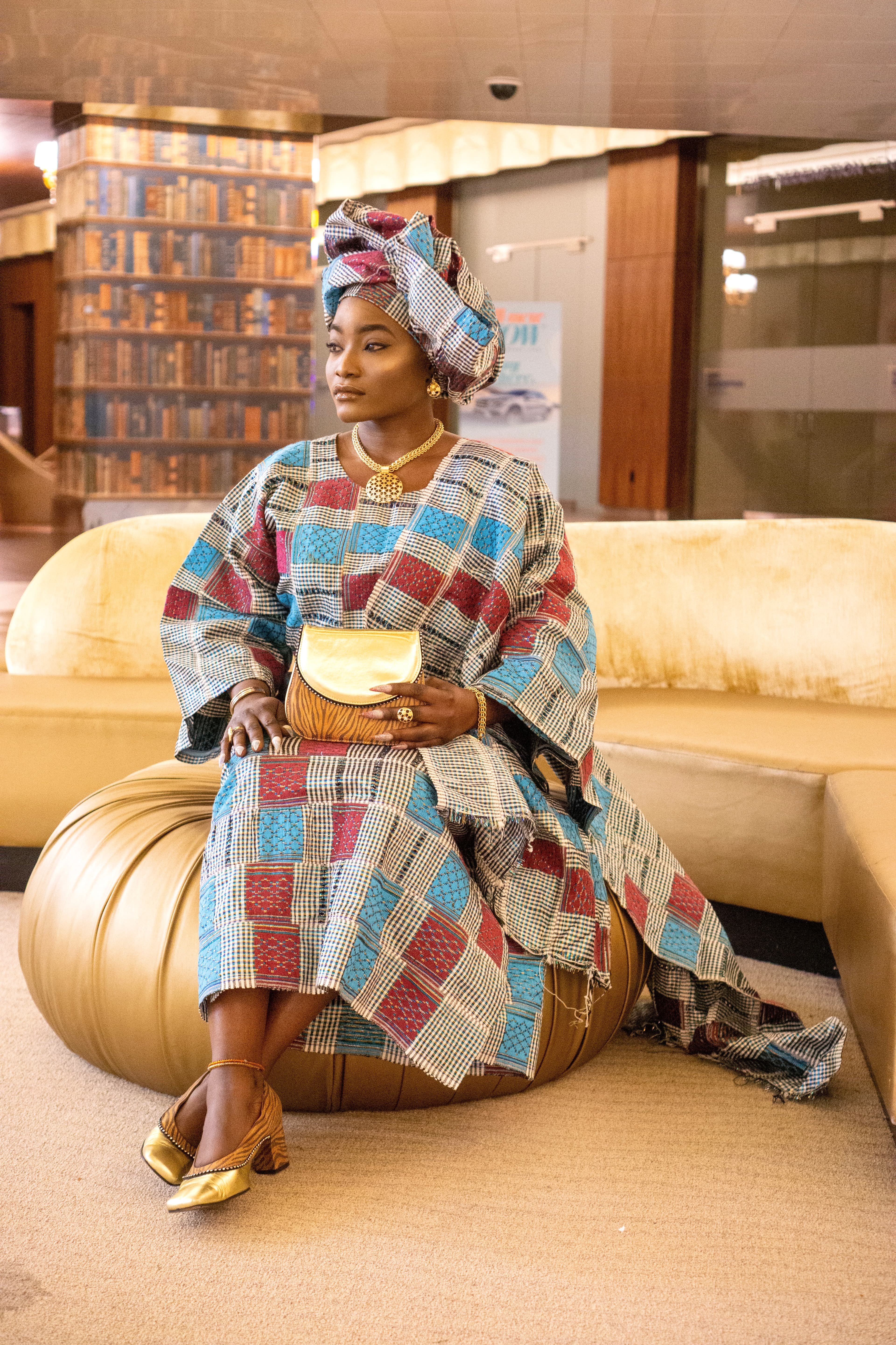 Editorial portrait, woman in African print seated in lobby