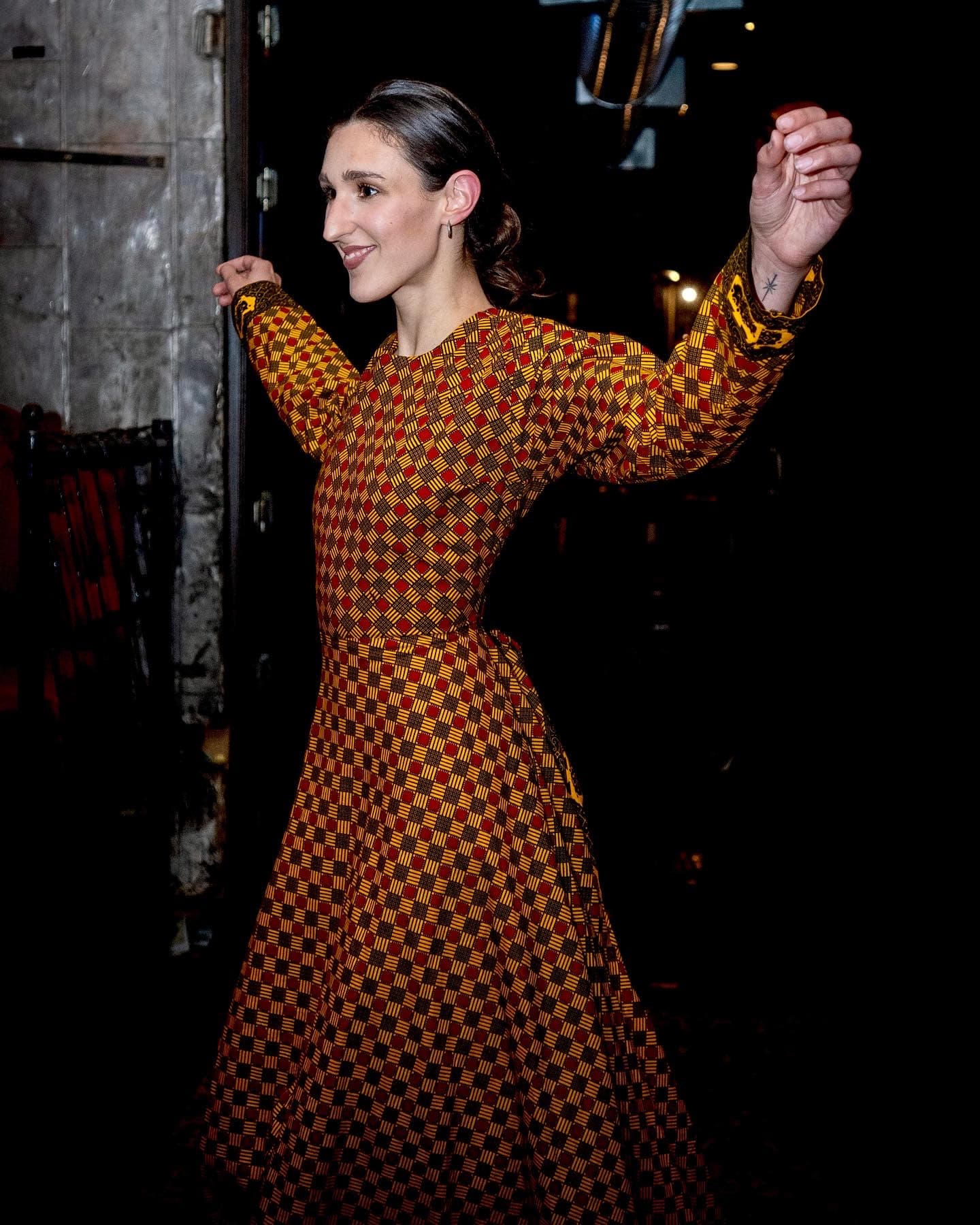 Fashion editorial, woman in patterned dress at dimly lit venue