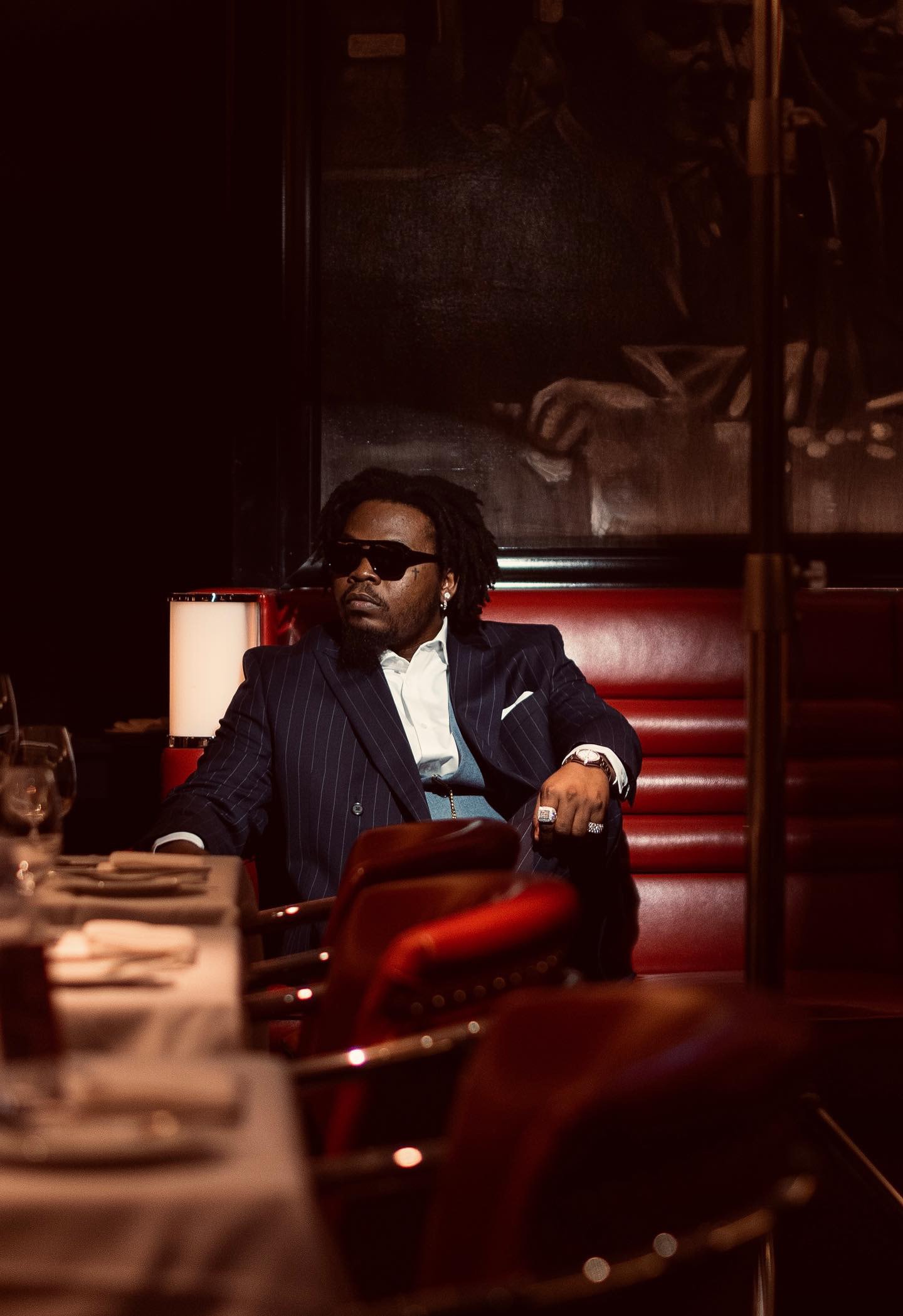 Cinematic portrait, man in navy pinstripe suit at dim restaurant